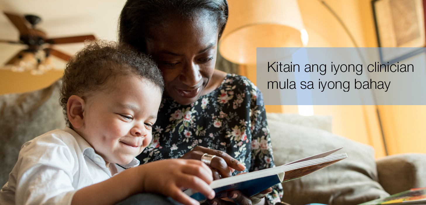 Black woman and child smiling, looking at book. They are sitting in a living room.